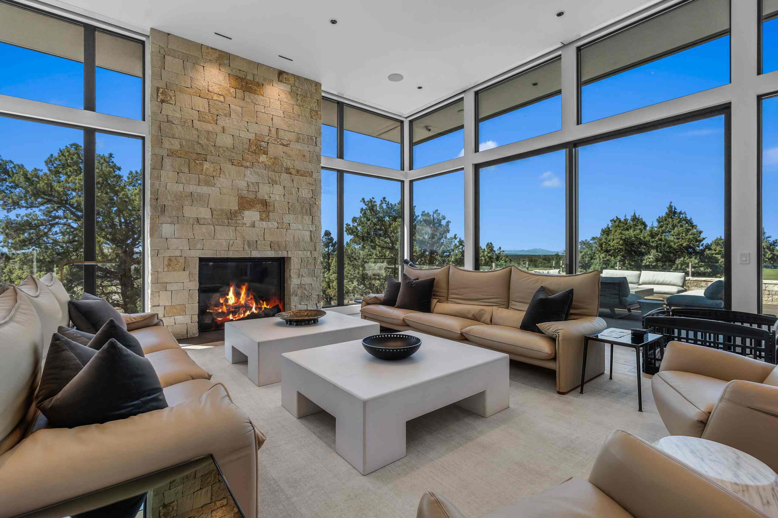 Bright living room with floor-to-ceiling windows and a stone fireplace in a Central Oregon vacation rental